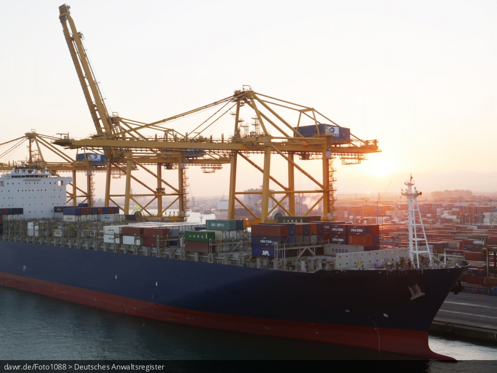 Dieses Foto zeigt einen Teil eines halbvoll beladenes Containerschiff im Hafen von Barcelona (Spanien). Über dem Schiff sind zwei große Verladekräne zu sehen.